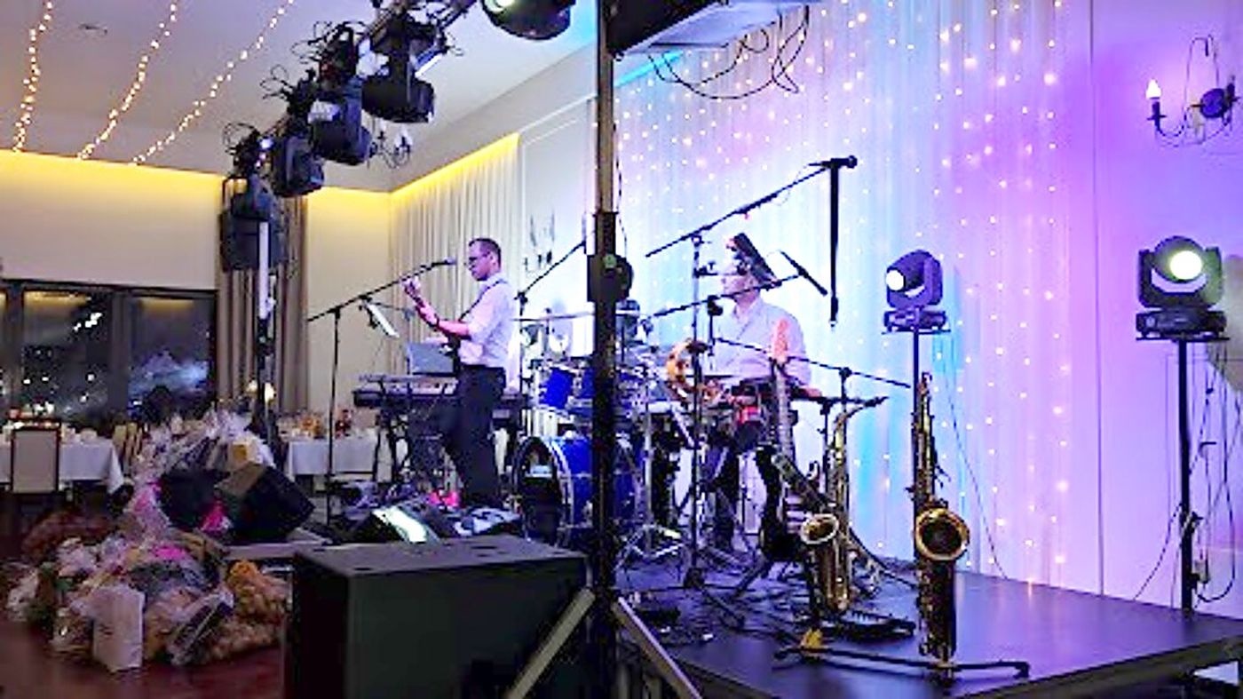 Zespół muzyczny na scenie z kurtyną świateł podczas wesela